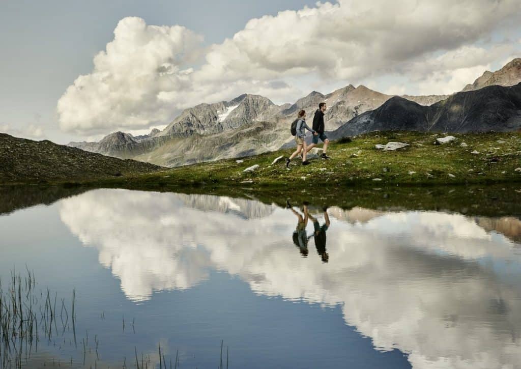 Bergwanderer auf einer Wanderung in den Alpen mit Blick auf Berge und einen ruhigen See.