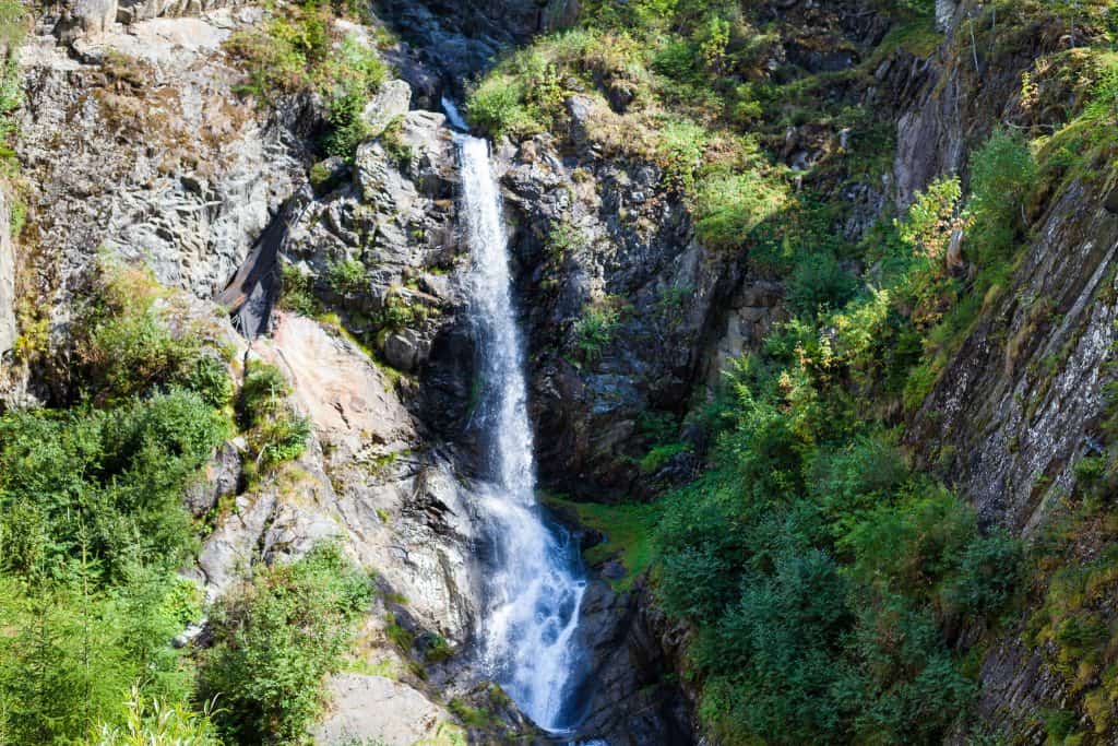 Naturwasserfall inmitten von Bäumen und Felsen, fließendes Wasser in einer malerischen Landschaft.